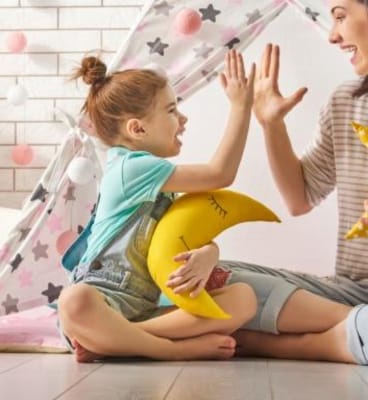 mama si fiica bat palma si cea mica tine o perna galbena in forma de luna