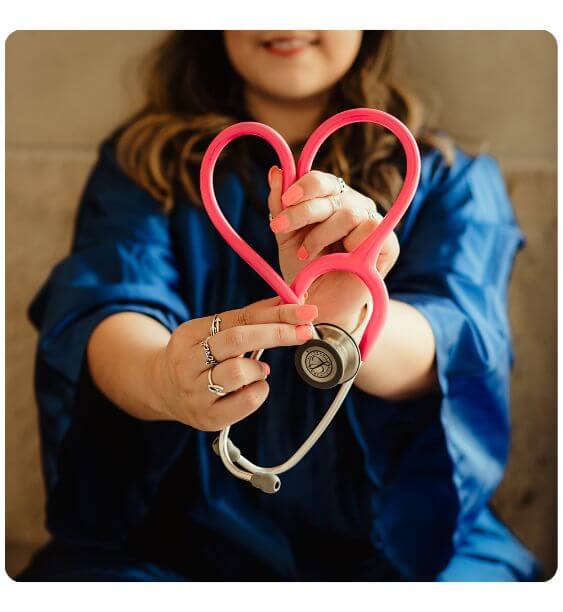 asistenta medicala tine in mana un stetoscop roz in forma de inima