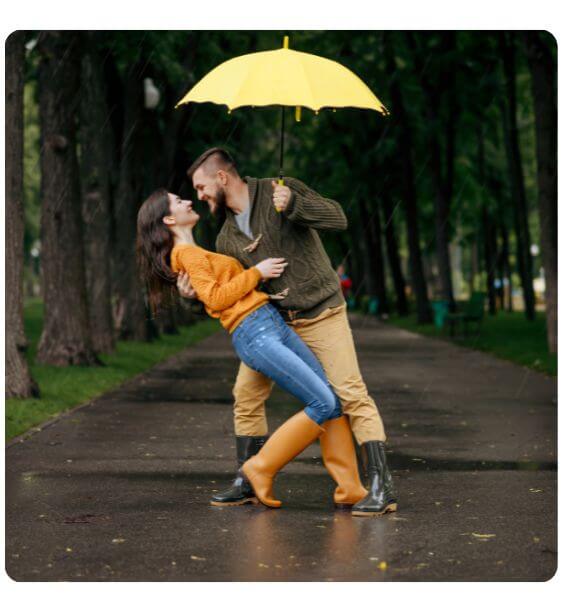cuplu danseaza in ploaie cu o umbrela galbena deasupra capului