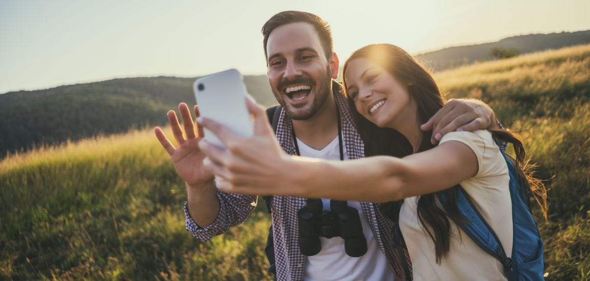 cuplu in drumetie la munte fac un selfie si zambesc