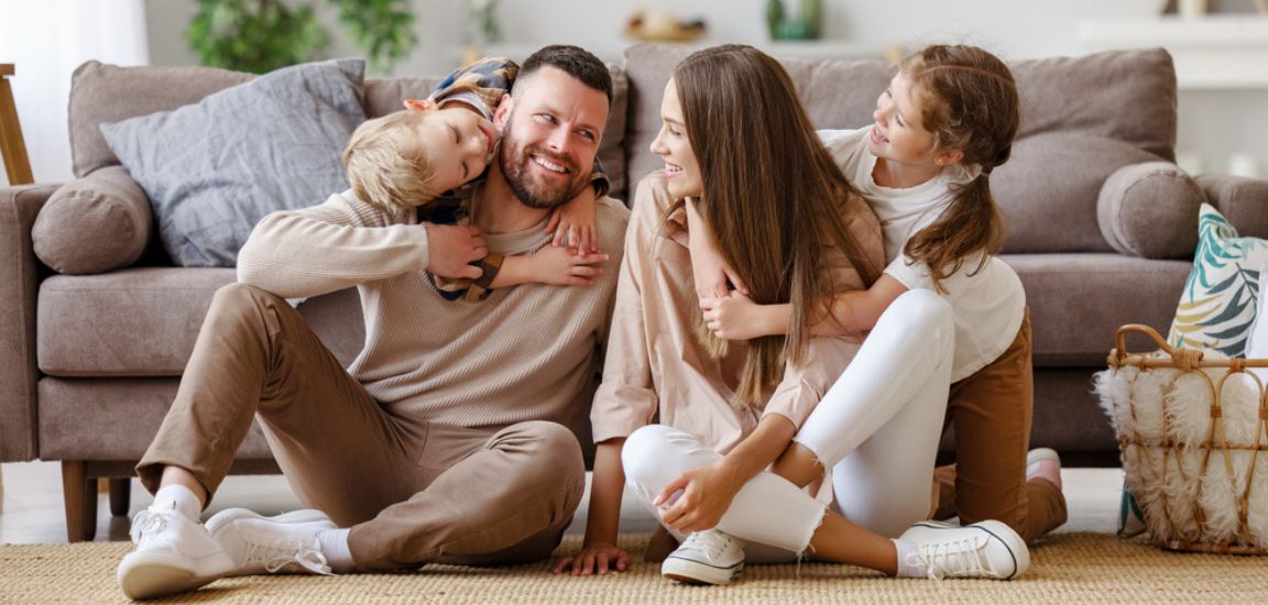 familie cu 2 copii se joaca pe covor in fata canapelei