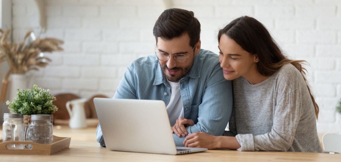 cuplu se documenteaza pe laptop