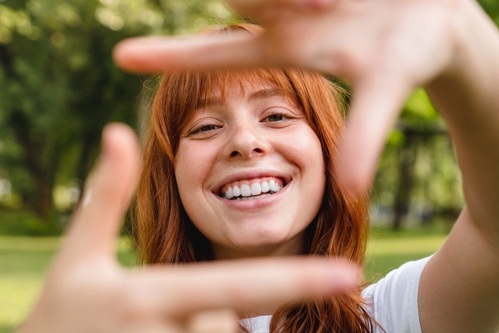 fata care zambeste printre degete la camera