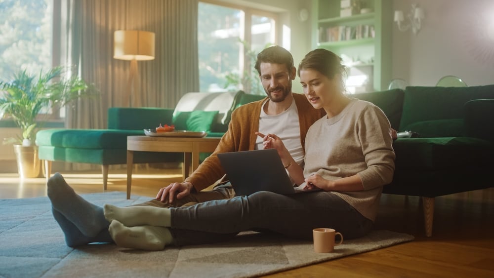 cuplu care stau impreuna si se uita in telefon