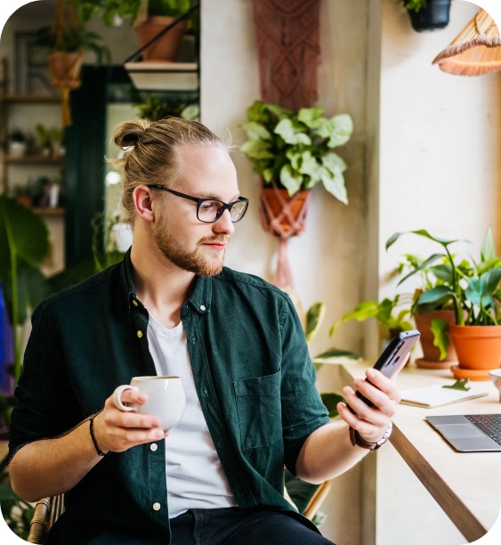 Un tip isi verifica telefonul mobil in timp ce savureaza cafeaua NN