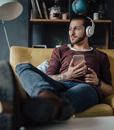 Barbat se uita la telefon pe canapea NN