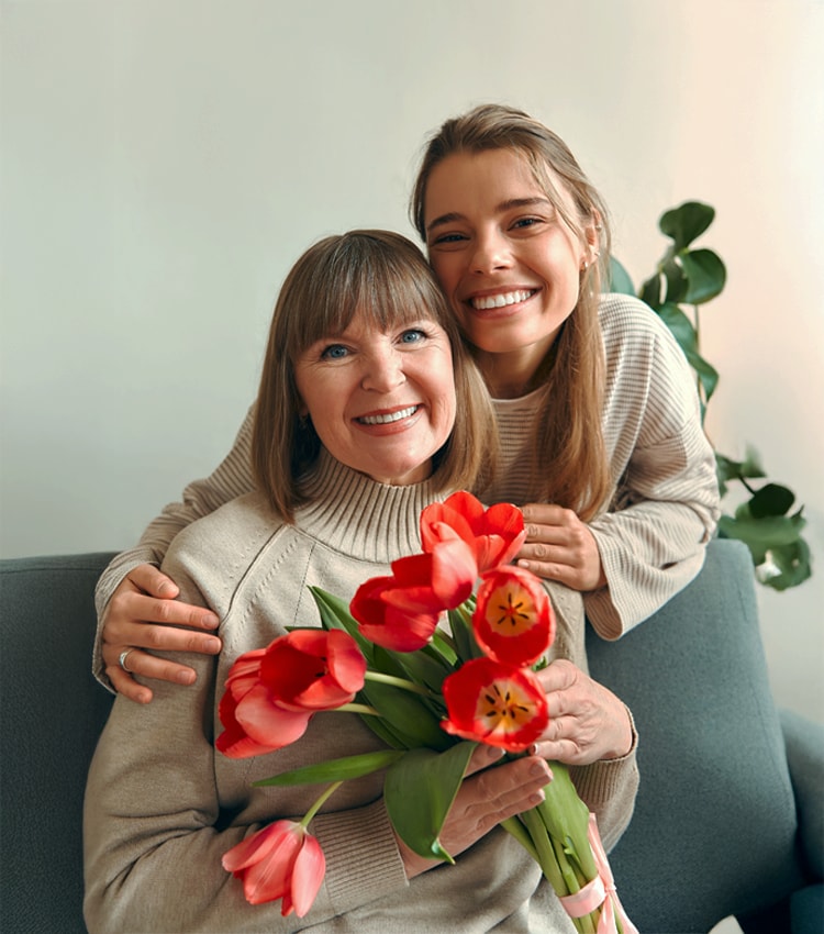 femeie tanara care isi imbratiseaza mama si ii ofera cadou asigurarea de sanatate NN