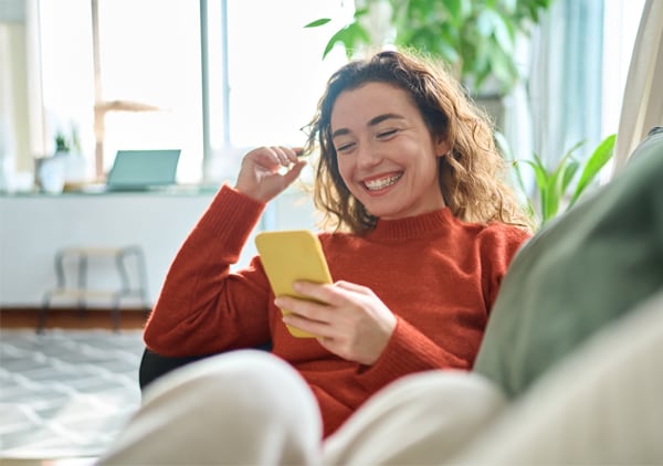 Fata care sta pe canapea si se uita pe telefon NN