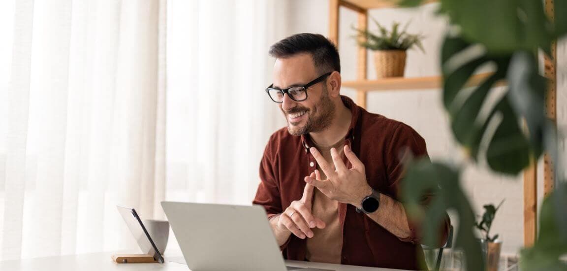 barbat tanar cu ochelari la laptop in timpul unui meeting online