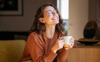 femeie roscata fericita cu o cana de cafea in mana