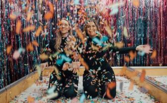 doua femei vesele inconjurate de confetti la o petrecere