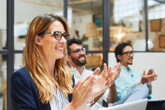 colegi de munca intr-o sala de sedinta asista la o prezentare