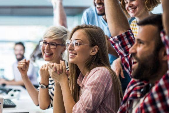 grup de corporatisti se bucura in fata unui calculator