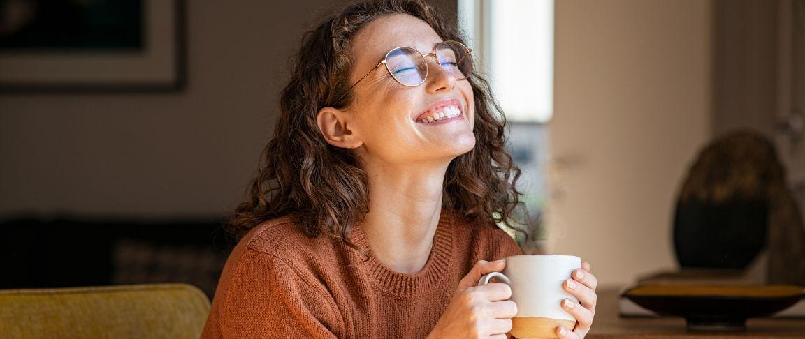 femeie roscata fericita cu o cana de cafea in mana