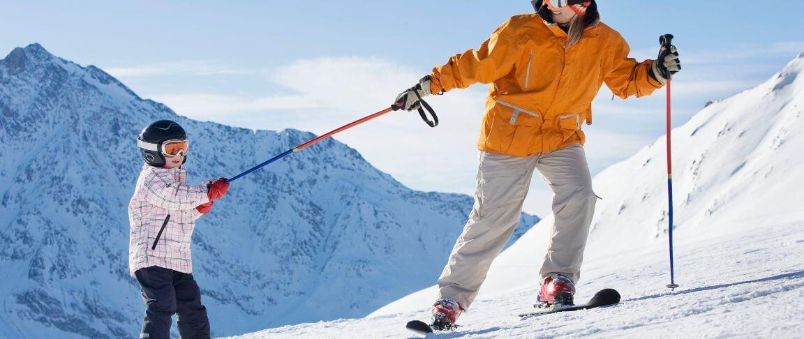 tatic cu o geaca galbena la ski cu baietelul pe o creasta montana acoperita cu zapada 