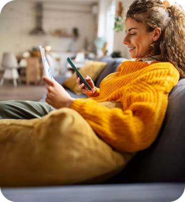 Femeie se relaxeaza in timp ce foloseste telefonul pe canapea NN Go