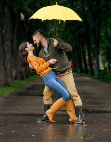 cuplu dansand in ploaie cu o umbrela galbena
